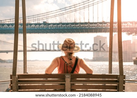 Young tourist woman on the Brooklyn Bridge and Manhattan Bridge. New York city girl walking in summer vacation USA travel lifestyle. Tourism in the USA NYC skyline in back.