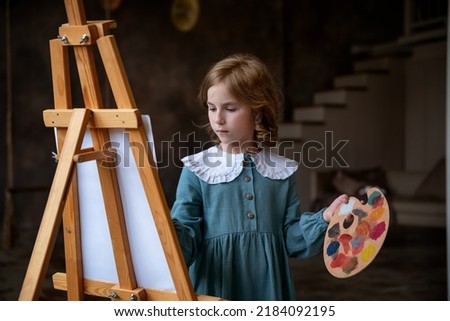 cute little girl draws behind an easel