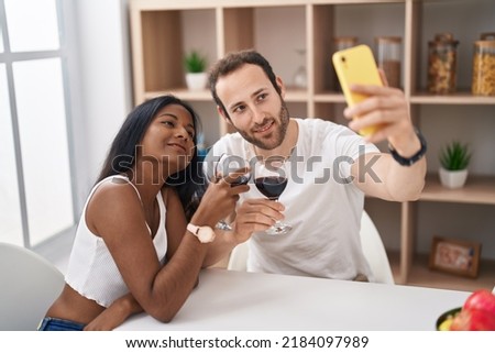 Man and woman interracial couple drinking wine make selfie by smartphone at home