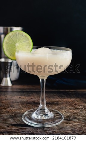 White Chocolate Gimlet Gin Cocktail with Ice Sphere: Cocktail made with gin, lime cordial, and white chocolate liqueur in a coupe glass Royalty-Free Stock Photo #2184101879