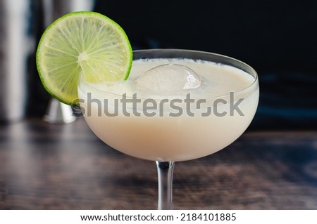 White Chocolate Gimlet Gin Cocktail with Ice Sphere: Cocktail made with gin, lime cordial, and white chocolate liqueur in a coupe glass Royalty-Free Stock Photo #2184101885