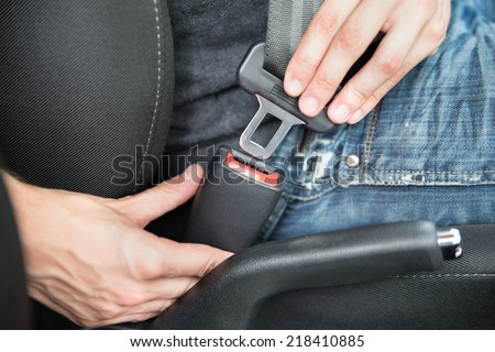 Closeup of man fastening seat belt in car Royalty-Free Stock Photo #218410885