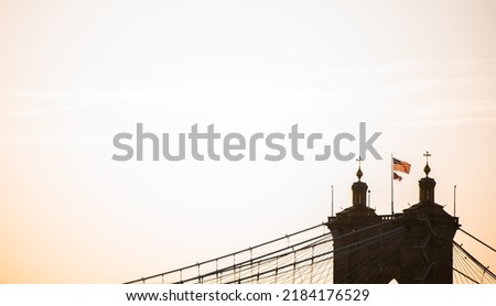 Top of a suspension bridge at golden hour with American flag on top of tower.