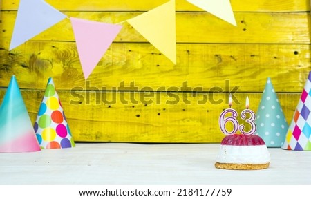 Colorful card happy birthday with festive decorations with cake and burning candles. Copy space. Beautiful happy birthday background on the background of yellow boards with a number of candles 63
