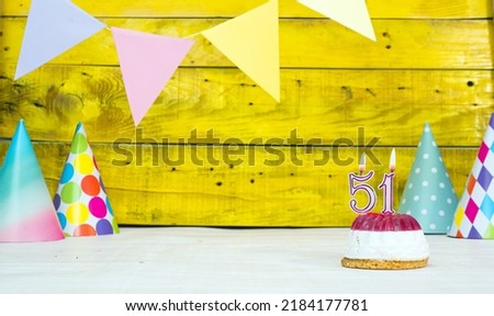Colorful card happy birthday with festive decorations with cake and burning candles. Copy space. Beautiful happy birthday background on the background of yellow boards with a number of candles 51