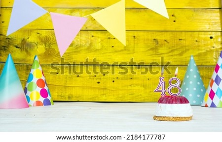 Colorful card happy birthday with festive decorations with cake and burning candles. Copy space. Beautiful happy birthday background on the background of yellow boards with a number of candles 48