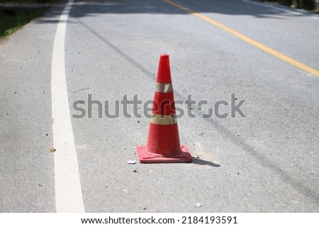 The top traffic cone is located on the road.