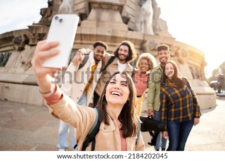 Group of multi-ethnic young people taking a happy smiling selfie. Students having fun outdoors. Beautiful woman shoot a photo in smartphone with a friends.