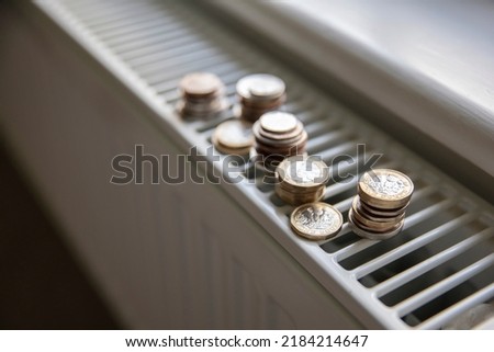 Cost of living crisis. Money on a home radiator heater. Rising cost of energy and bills Royalty-Free Stock Photo #2184214647