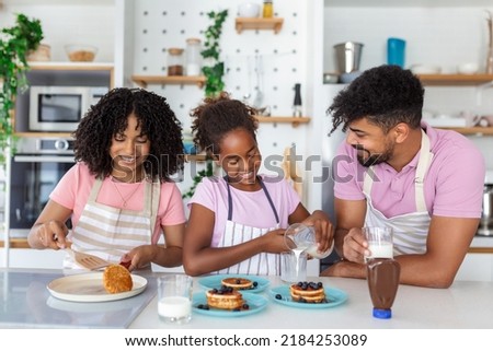 Overjoyed young family with little daughter have fun cooking baking pastry or pancakes at home together, happy smiling parents enjoy weekend play with small child doing bakery cooking in kitchen