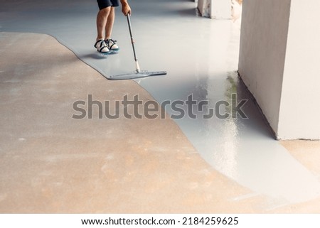 Epoxy floor installation over existing concrete using roller and rubber spatula Royalty-Free Stock Photo #2184259625