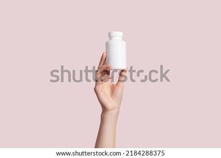 Young female hand holding blank white squeeze bottle plastic tube on pink background. Packaging for pill, capsule or supplement. Product branding mockup. High quality photo Royalty-Free Stock Photo #2184288375