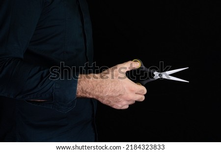 Scissors in hand on black background