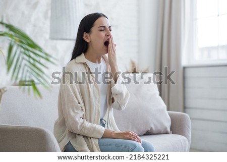 Beautiful woman at home sitting on the sofa tired yawning, sleepless brunette Royalty-Free Stock Photo #2184325221