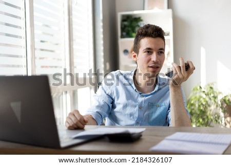 Young businessman hold phone by mouth use voice dialing or information search
