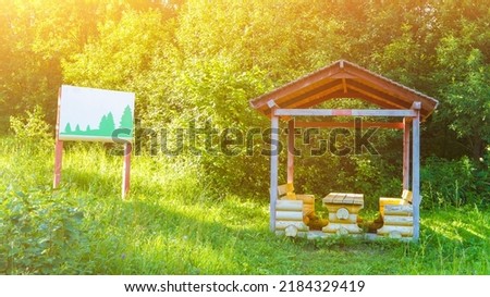 Wooden arbor and placard with pine picture at forest resort. Equipment for tourist rest. Wild nature and environment. Camping at forestry site