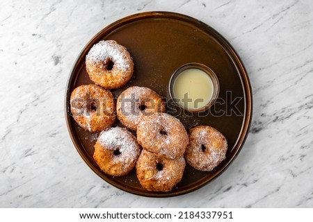 Airy cottage cheese donuts with condensed milk in a  plate on a marble background. Restaurant banquet menu.