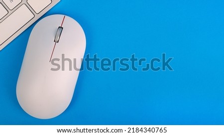 Computer mouse and keyboard on a blue background top view. Place for text.