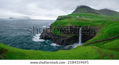 Incredible panoramic view of Mulafossur waterfall in Gasadalur village with background island Mykines. Vagar Island of the Faroe Islands, Denmark. Landscape photography