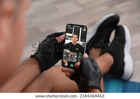 Man having workout with personal trainer via smartphone at home, closeup Royalty-Free Stock Photo #2184364463