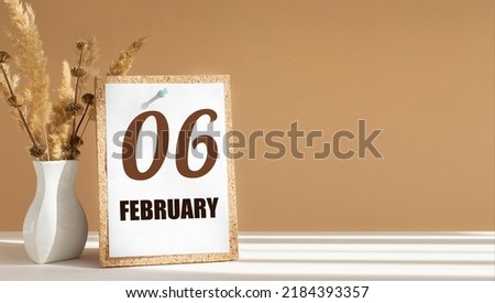 february 6. 6th day of month, calendar date.White vase with dead wood next to cork board with numbers. White-beige background with striped shadow. Concept of day of year, time planner, winter month.
