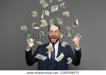 Portrait of happy businessman with heap of money on grey background