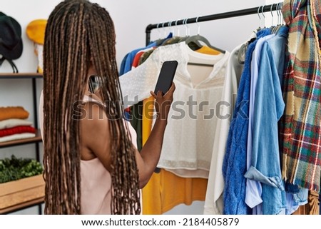 Young african american customer woman make photo by the smartphone to clothes at clothing store.