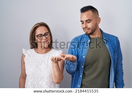 Hispanic mother and son standing together smiling showing both hands open palms, presenting and advertising comparison and balance 