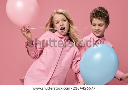 horizontal portrait of happy children in pink clothes playing with pink and blue balloons