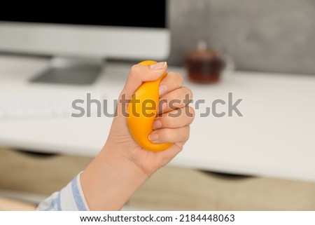 Woman squeezing antistress ball in office, closeup Royalty-Free Stock Photo #2184448063