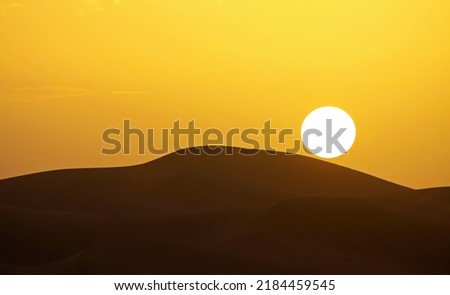 Gold yellow sunset with circular full round sun ball over silhouette of desert sand dunes sky - Morocco, Sahara Erg Chebbi, North Africa Royalty-Free Stock Photo #2184459545