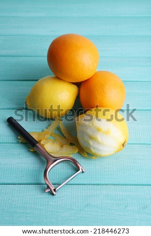 Lemons and oranges and peeling knife on blue wooden background