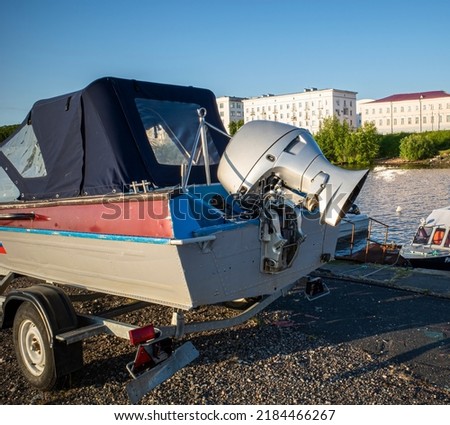 duralumin boat with outboard motor on a trolley before launching, city background and blue sky