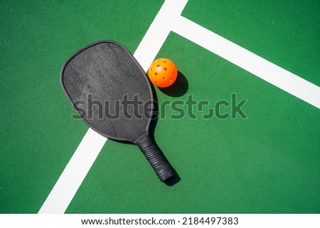 Pickleball paddle and pickle ball on court.                             Royalty-Free Stock Photo #2184497383