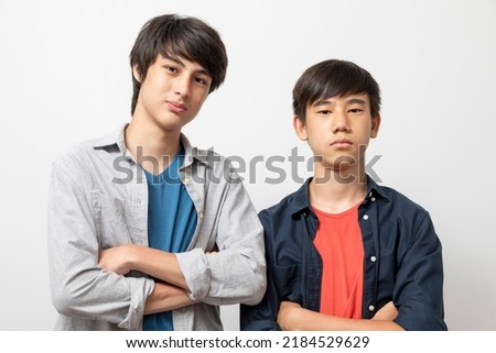 Caucasian and Asian teen boys wear shirt and stand on white background. Concept of mix raced. Royalty-Free Stock Photo #2184529629