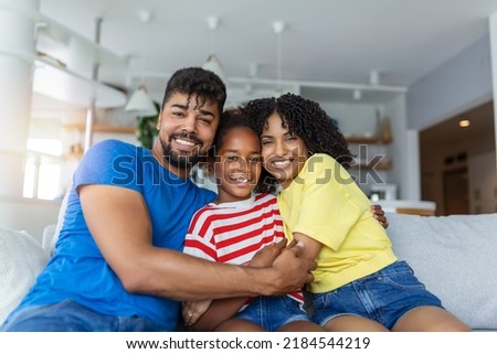 Portrait attractive multi-ethnic wife husband and kid indoors. Close up married couple with little pretty daughter sitting together smiling looking at camera. Concept friendly wellbeing happy family