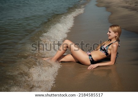 young blond woman in swimsuit at sea surf with foam relax