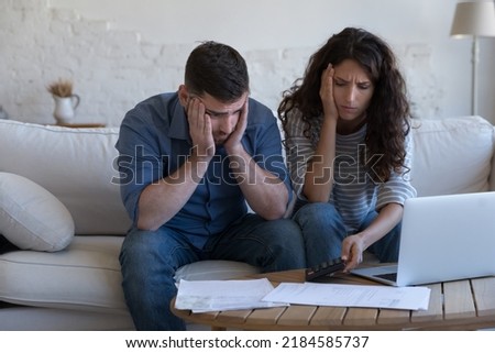 Concerned upset millennial couple counting overspent budget, doing paperwork, thinking on financial problems, high mortgage, rental fees, bad loan conditions, bankruptcy, eviction notice Royalty-Free Stock Photo #2184585737