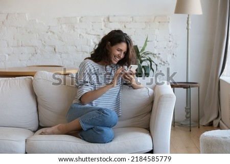 Excited happy young adult woman reading message on mobile phone, getting good news on screen, smiling, laughing, talking on video call, chatting on Internet, using online app. Communication concept Royalty-Free Stock Photo #2184585779