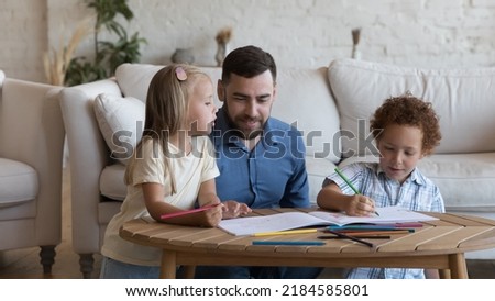 Happy dad enjoying creative leisure time with two sibling kids, watching children drawing in colorful pencils in album, talking, helping, giving support. Family playtime, fatherhood concept. Banner