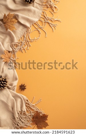 Autumn concept. Top view vertical photo of scarf anise yellow maple leaves and pine cones on isolated orange background with copyspace