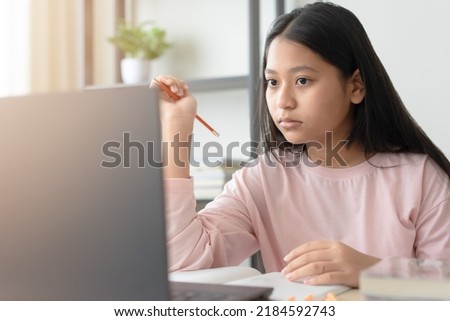 Asian school girl studying online class on laptop. Happy kid enjoy learning from home using laptop.