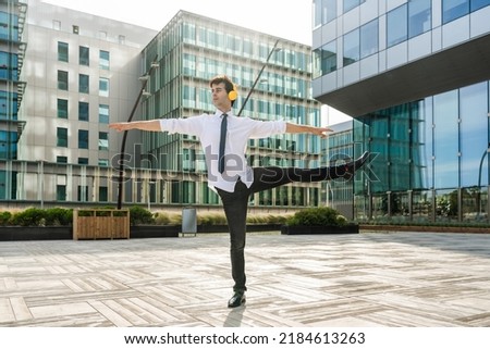 Happy and handsome adult businessman wearing elegant suit doing acrobatic trick moves in the city, alternative concept for business advertisement with energetic and creative people