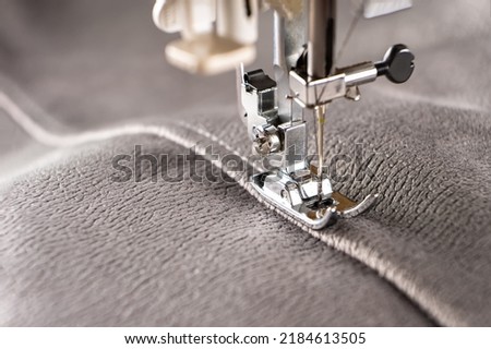 Modern sewing machine presser foot with linen fabric and thread, closeup, copy space. Sewing process clothes, curtains, upholstery. Business, hobby, handmade, zero waste recycling, repair concept, DIY Royalty-Free Stock Photo #2184613505