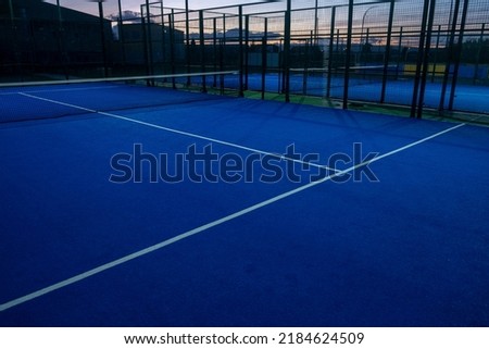view of a blue paddle tennis court at nightfall, racket sports Royalty-Free Stock Photo #2184624509