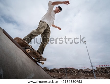 young male skater skates over the edge of a bowl at a skate park