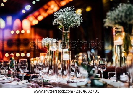 Luxury table settings for fine dining with and glassware, pouring wine to glass. Beautiful blurred background. Preparation for holiday wedding. Fancy luxury restaurant. Royalty-Free Stock Photo #2184632701