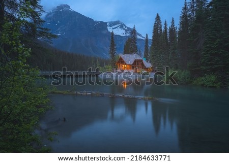 Moody, atmospheric golden light from traditional log cabin Emerald Lake Lodge at night in Rocky Mountains in Yoho National Park, BC, Canada. Royalty-Free Stock Photo #2184633771