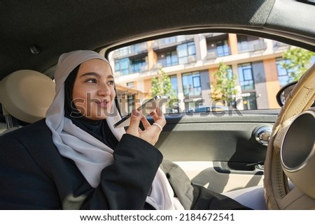 Beautiful muslim woman talking on the phone in the car