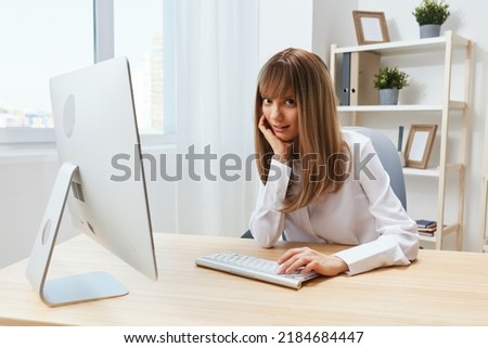 Happy smiling adorable blonde businesswoman typing answer for client look at camera sitting at workplace in modern office. Cheerful employee work on computer online in support service. Copy space
